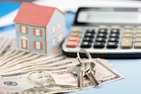 Calculator, cash and house keys, symbolizing the costs of homes for first time buyers